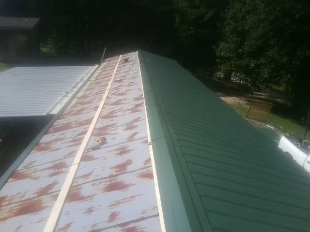 Old rusted panels beside newly installed green metal roofing — Wind Damage Roof Repair by Roofing Brothers in Stamford