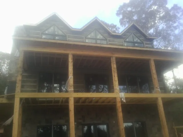 Dormers and porch framing on a large log home under construction — Roof Coating work by our crew in Stamford
