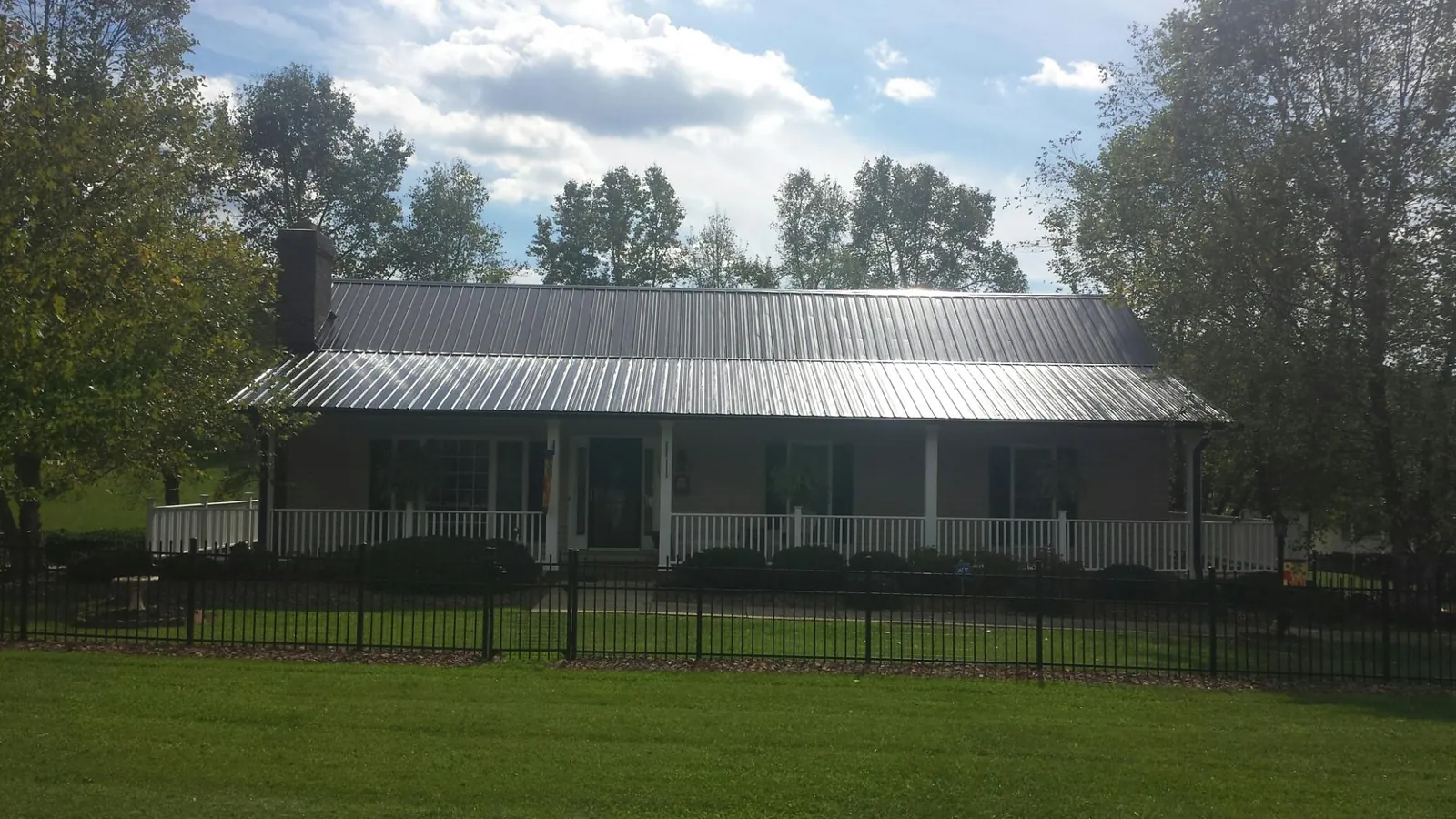 Gray metal roof on a brick ranch with a full width front porch — Gutter Guard Installation work by our crew in Stamford