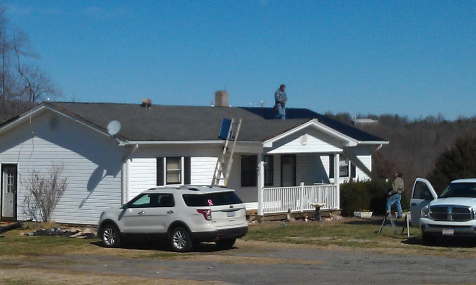 Roofers stripping shingles from a white ranch house roof in Stamford