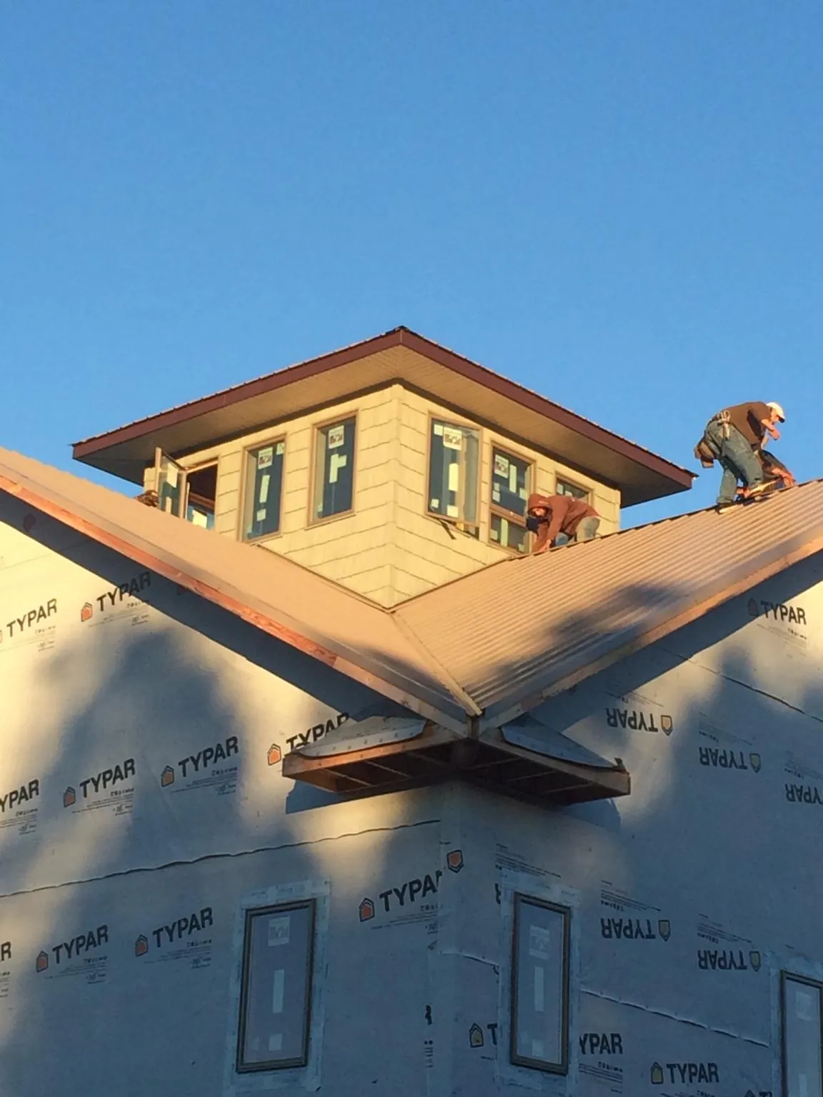 Roofers working around a rooftop cupola on a new metal roof at sunset — Roof Waterproofing in Stamford by Roofing Brothers